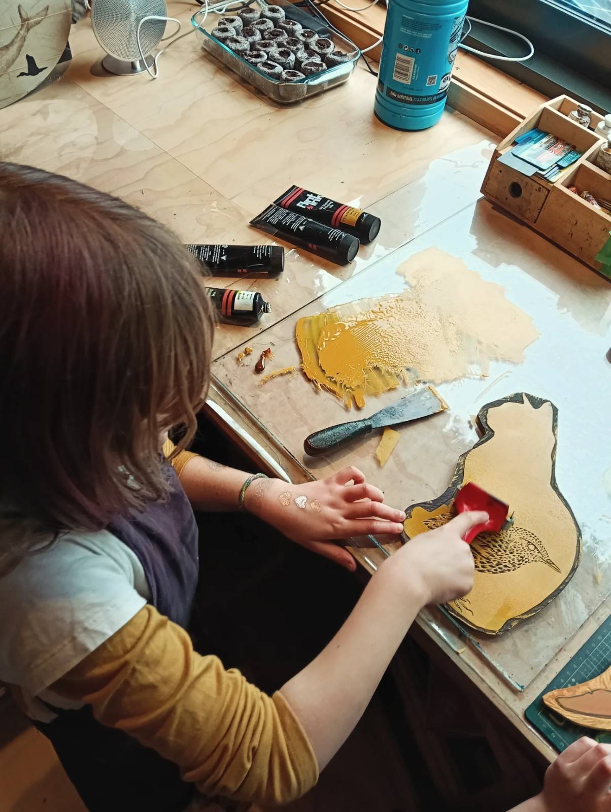 A girl rolling ink onto a cat-shaped woodblock