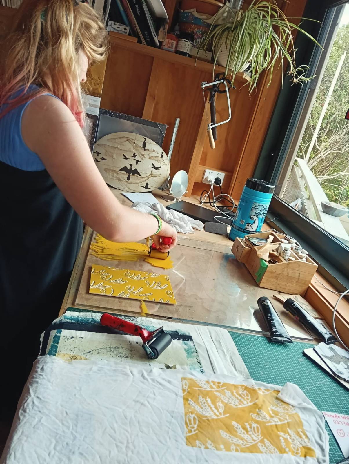 A girl rolling yellow ink onto a plate